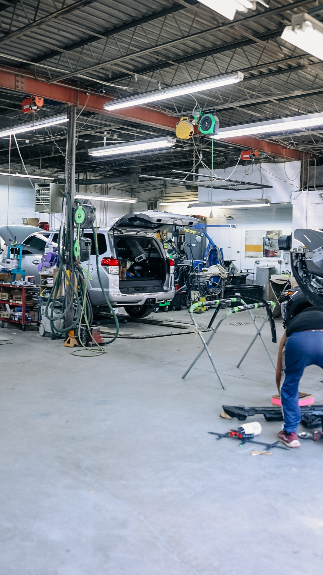 Technician performing detailed paint prep work on vehicle panel at Quality Auto Body in Fairfax, VA